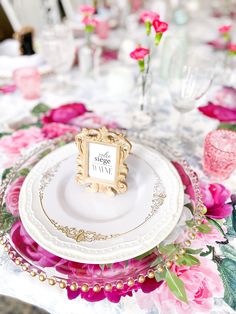 there is a place setting on the table with pink flowers and gold trimmings