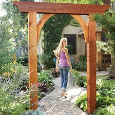 a woman walking through a garden with lots of plants