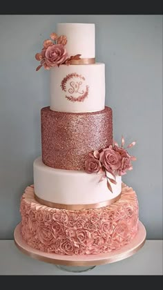 a three tiered wedding cake with pink flowers on the top and gold trimmings