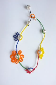 a multicolored beaded necklace with flowers and pearls on a white table top