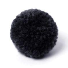 a black wool ball sitting on top of a white surface