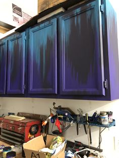 the cabinets are painted purple and blue with black paint on them, along with other tools