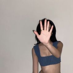 a woman with her hand up in the air while wearing a crop top and jeans