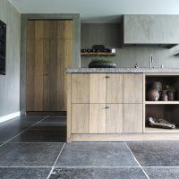 a kitchen with gray tile floors and wooden cabinetry on the wall, along with an area rug