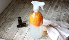 a bottle of liquid sitting on top of a wooden floor next to a spray bottle