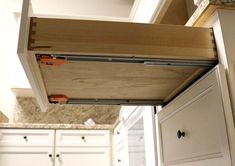 an open drawer in a kitchen with white cabinets