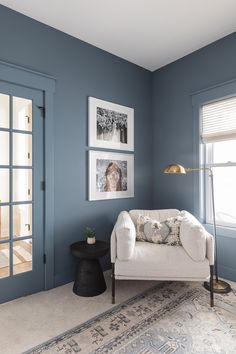 a living room with blue walls and pictures on the wall above the couch, along with a coffee table