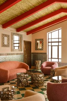 a living room filled with lots of furniture next to large windows and tiled flooring