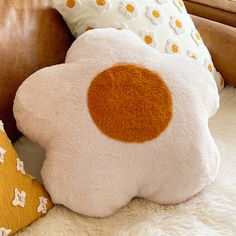 two pillows are sitting next to each other on a bed with white fur and brown leather headboard