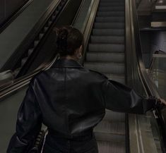 a woman in black jacket walking down an escalator