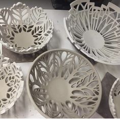 four white bowls sitting on top of a table covered in paper maching and scissors