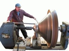 a man is working on a machine with a large metal object in front of him