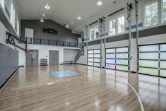 an indoor basketball court with hard wood floors and glass doors on the side wall is shown