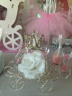 there is a small silver carriage with a rose in it on the table next to other items