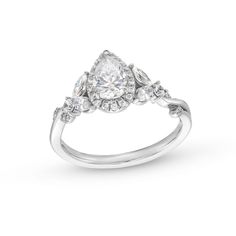 a white gold ring with three pear shaped diamonds on the sides and an oval diamond in the center