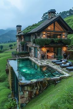 an outdoor swimming pool in front of a house with grass on the roof and windows