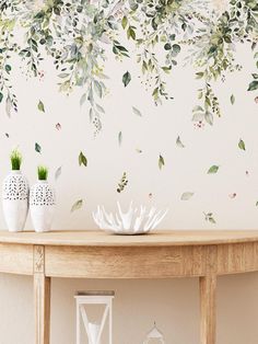 a table with two vases on top of it and a wall mural behind it