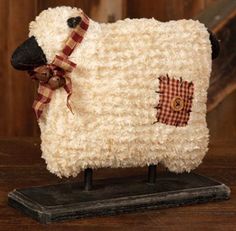 a stuffed sheep with a bow on it's head sitting on a wooden table