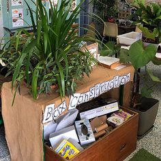 an open box with books and plants in it sitting on the floor next to a table