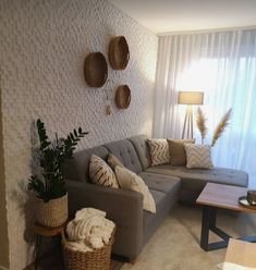 a living room filled with furniture and lots of pillows on the wall next to a window