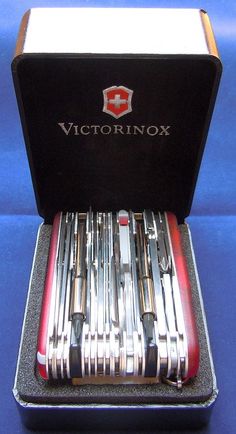 a set of swiss army knifes in a case on a blue tableclothed surface