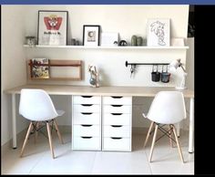 two white chairs sitting in front of a desk with drawers and shelves on the wall