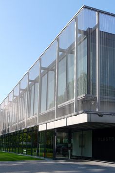 an empty parking lot next to a tall building with glass walls on the top floor