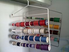 a rack that has some spools of thread hanging from it's sides