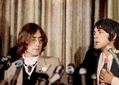 two men sitting in front of microphones talking to each other