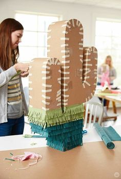 a woman standing next to a cardboard cactus