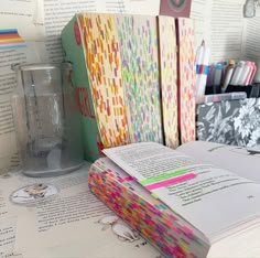 an open book sitting on top of a table next to some pens and pencils