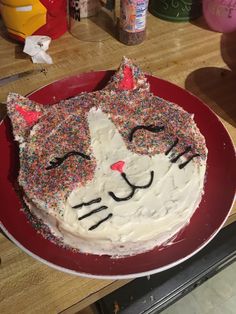 a cat cake with sprinkles on it sitting on a red platter