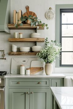 a kitchen with green cabinets and shelves filled with plates, bowls and vases on the counter