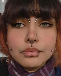 a woman with piercings on her nose and nose ring in front of her face