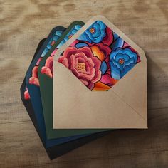 four envelopes with colorful flowers on them sitting on a table next to each other