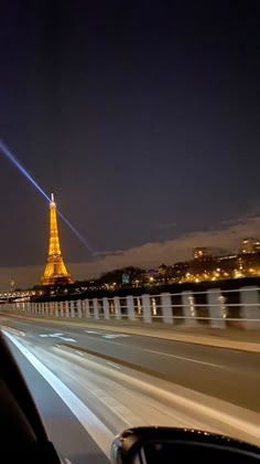 the eiffel tower lit up at night in paris, france as seen from a moving car