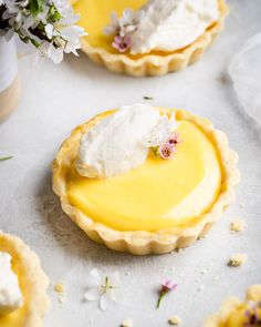 lemon tarts with whipped cream and flowers in the background