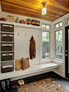 a room with a bench, window and coat rack on the wall next to it