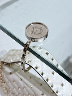 a close up of a ring on top of a glass table with beaded edges