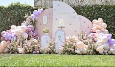 there is a pink house with balloons all over the front and back yard, surrounded by flowers and greenery