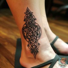 a woman's foot with a tattoo design on the bottom and an intricate knot around it