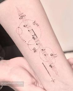 a woman's arm with musical notes on it and an arrow tattoo design in the middle