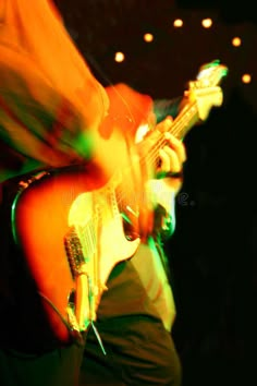 a blurry photo of a man playing an electric guitar at a concert royalty images