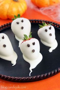 chocolate covered strawberries in the shape of ghostes are sitting on a black plate