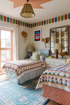 two beds in a room with colorful decor on the walls and ceiling, along with a large window