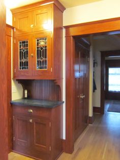 an empty room with wooden cabinets and black counter top in the center, along with hard wood flooring