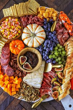 a platter filled with different types of cheeses, crackers and fruit on top of a wooden table