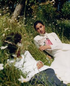 a woman laying in the grass next to a man who is wearing a white coat