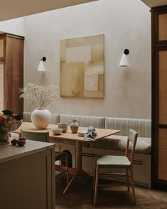 a dining room table with two chairs and a vase on the table next to it