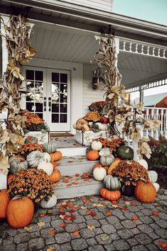 pumpkins and gourds are arranged on the porch